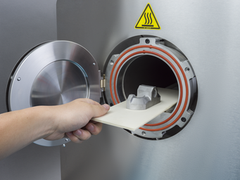 a person removing a 3d pritned part from the markforged sintering furnace