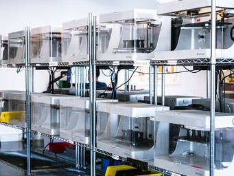 Rack of Markforged 3D printers producing parts